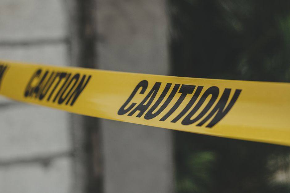 Close-up view of yellow caution tape creating a warning barrier outdoors.