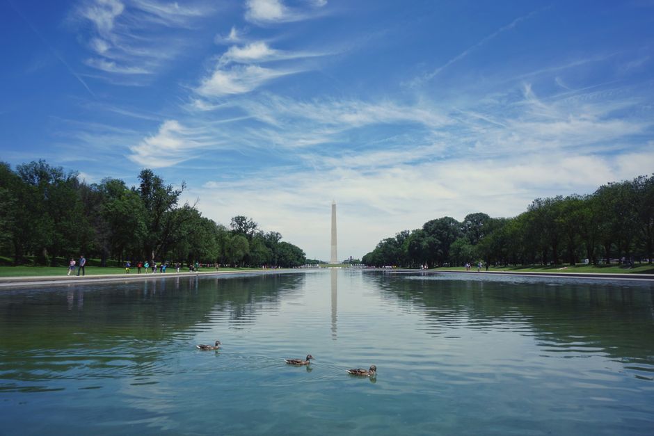 A serene view of the Washington Monument reflecting in a pool with a vibrant sky above.