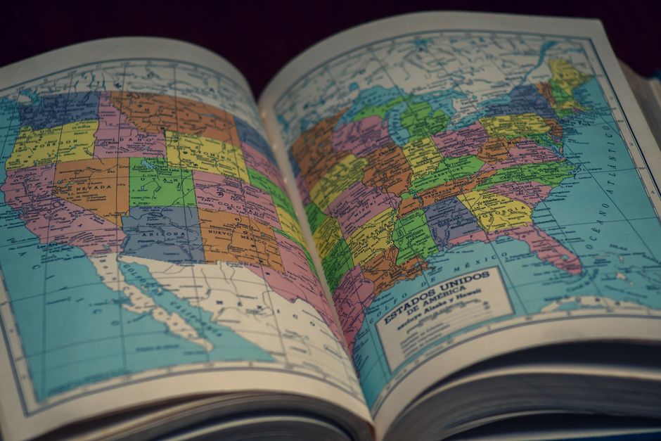Open atlas showing a colorful map of the United States, highlighting states with vibrant colors.