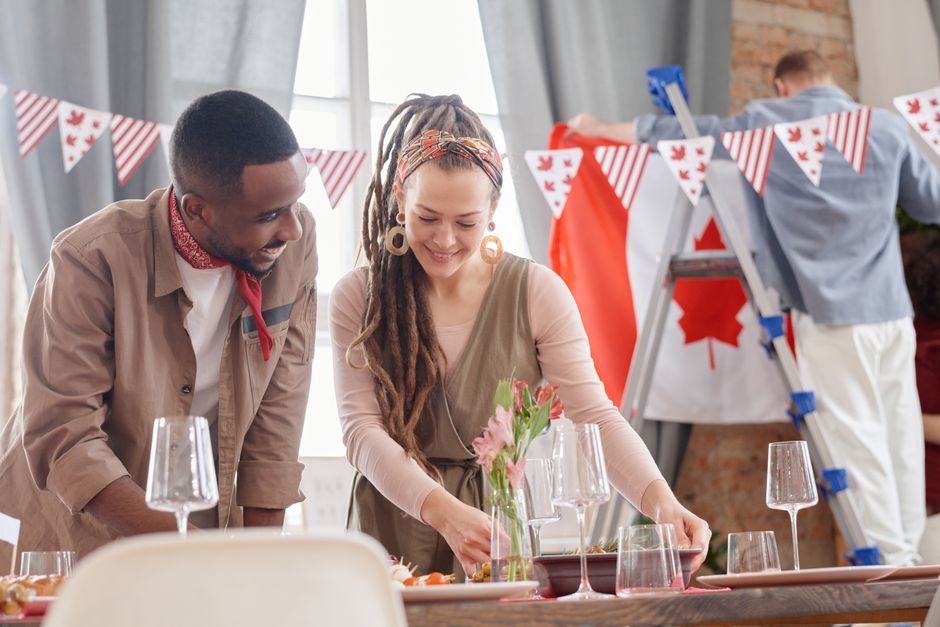 Friends set a festive Canadian-themed tablescape, celebrating with joyful preparations indoors.