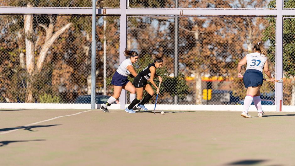 Dynamic scene of a women's field hockey match with players in action outdoors.