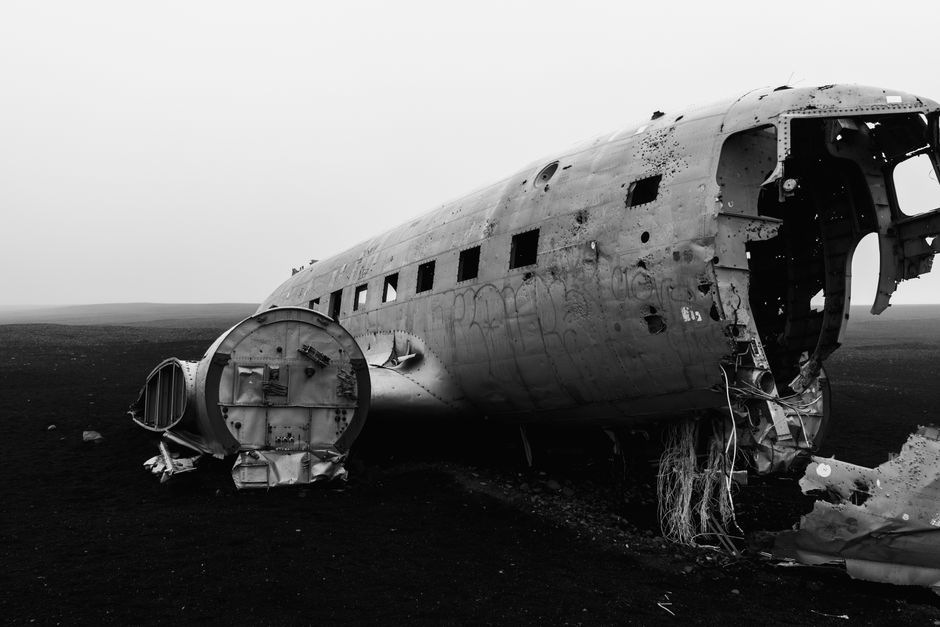 Eerie black and white image of abandoned plane wreck on desolate landscape.